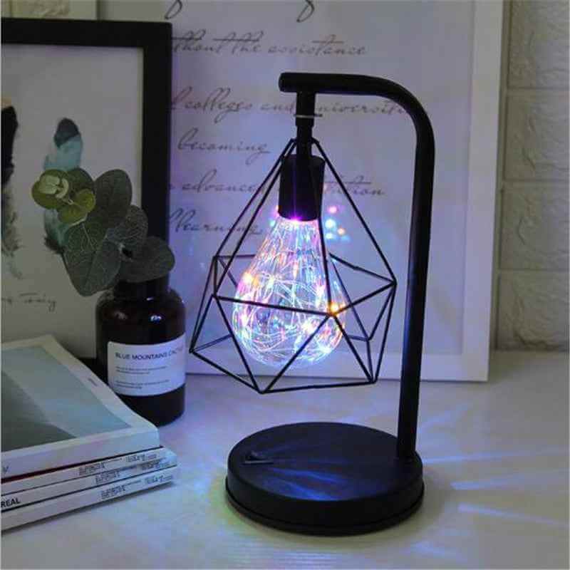Modern decorative table lamp with artistic iron design, glowing LED light and stylish geometric shape on a desk.