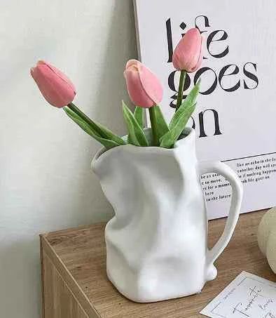Wrinkled texture ceramic vase holding pink tulips, decorative accent for modern interiors.