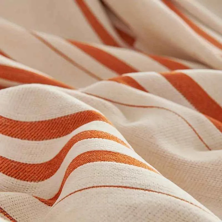Close-up of a machine washable chenille throw blanket with orange stripes showing its texture and rich colors.