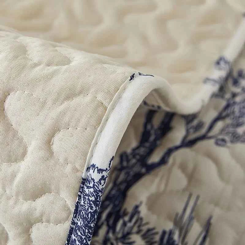 Close-up of a beige and blue stretch fabric sofa cover showcasing its intricate quilted design.