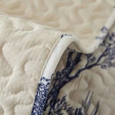 Close-up of a beige and blue stretch fabric sofa cover showcasing its intricate quilted design.