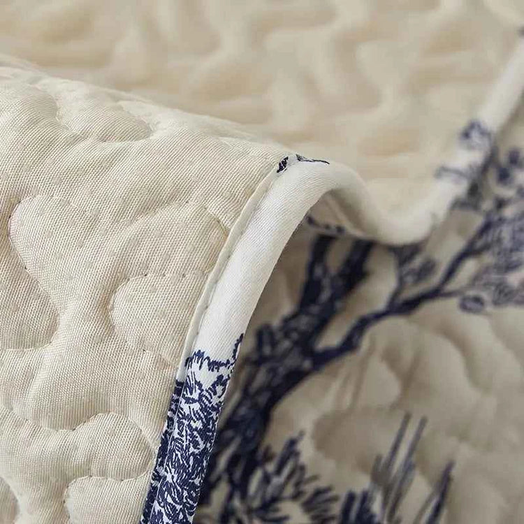 Close-up of a beige and blue stretch fabric sofa cover showcasing its intricate quilted design.